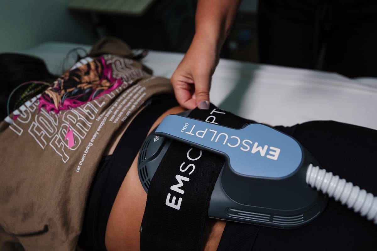 Provider positioning an Emsculpt Neo applicator on a reclining client's abdomen during a body sculpting session